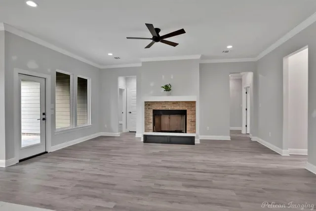 an empty room with wooden floor ceiling fan and windows