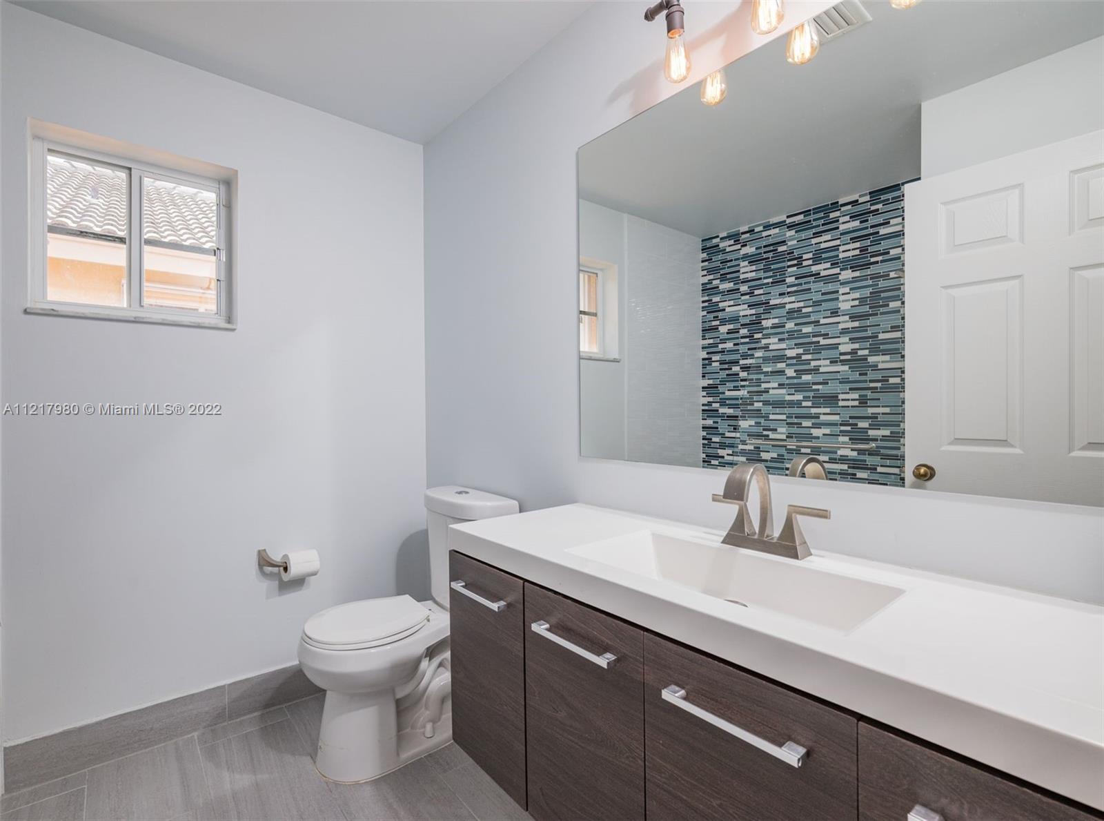 1418 Sandpiper Circle Weston, FL 33327 - Photo 19 of 31 a bathroom with a sink a toilet and mirror