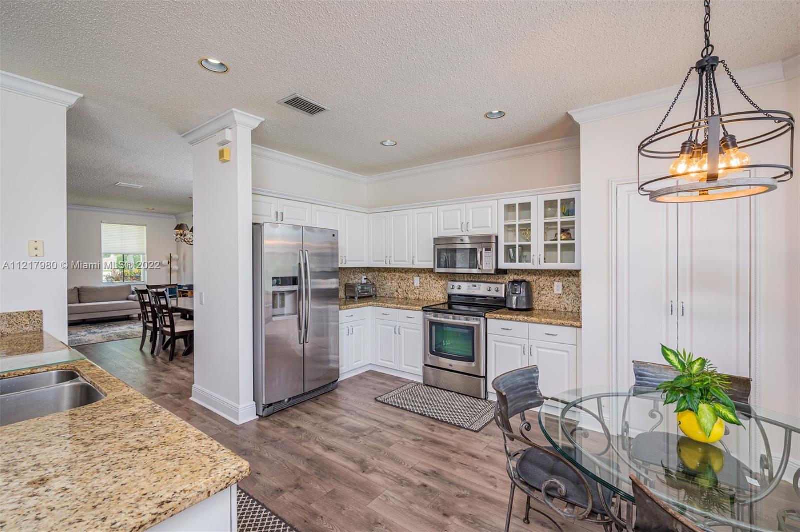 1418 Sandpiper Circle Weston, FL 33327 - Photo 7 of 31 a kitchen with stainless steel appliances granite countertop a stove refrigerator and a dining table with wooden floor