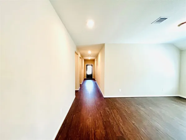 an empty room with wooden floor chandelier and windows