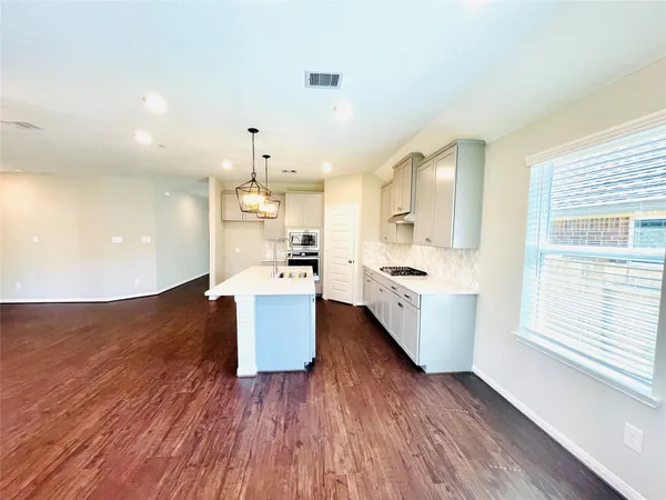 a large kitchen with cabinets wooden floor and stainless steel appliances