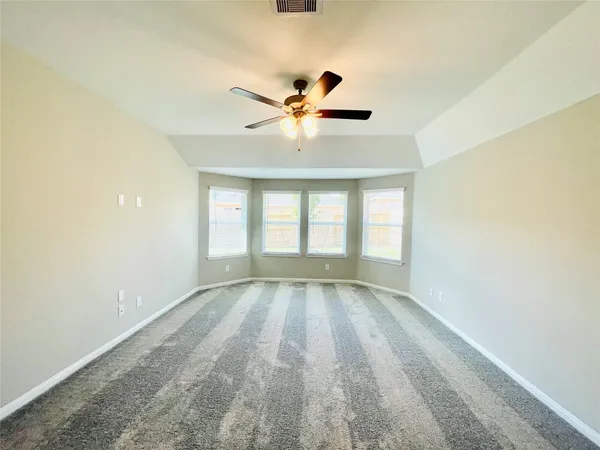 a view of an empty room with window and a kitchen