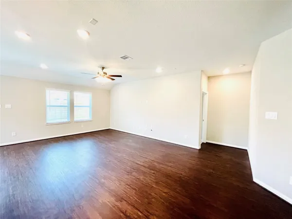 an empty room with wooden floor chandelier and windows