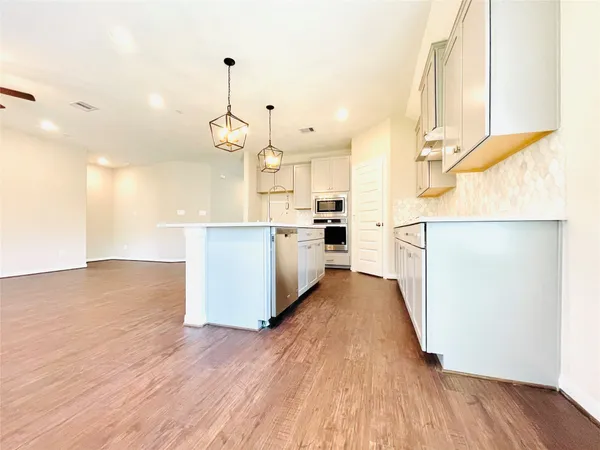 a kitchen with stainless steel appliances granite countertop a refrigerator a stove and a wooden floors