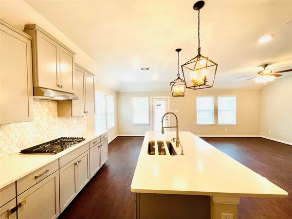 a kitchen with stainless steel appliances granite countertop a stove a sink dishwasher and white cabinets with wooden floor