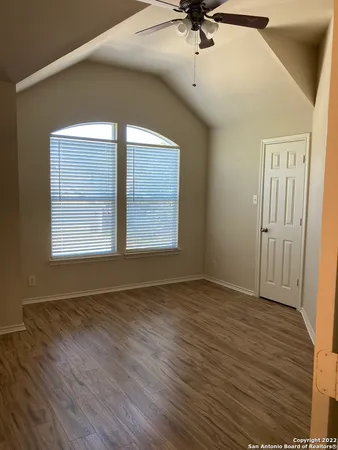 an empty room with wooden floor fan and windows