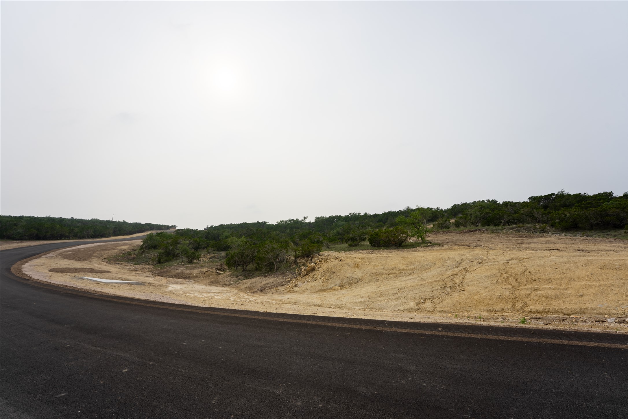 Lot 21 Ranch Road 165 Dripping Springs, TX 78620 - Photo 8 of 8 Paved road frontage bordering undeveloped land with natural scrub brush and varying topography