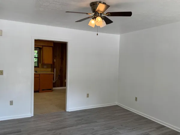 a view of an empty room with wooden floor and window