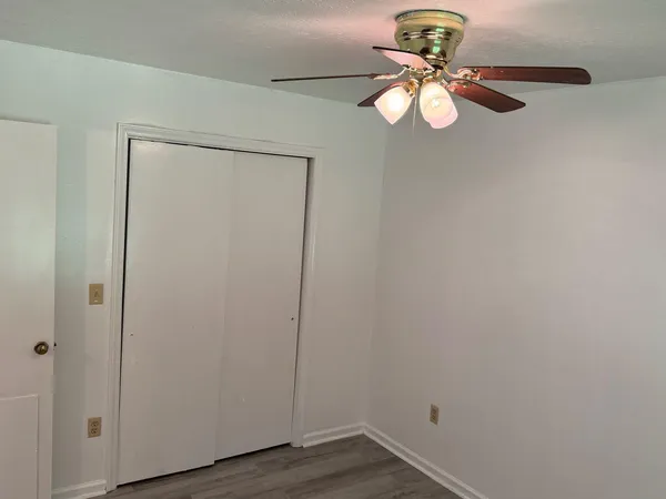 a view of a small space with wooden floor and a chandelier fan