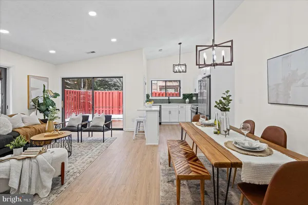 a view of a dining room and livingroom with furniture wooden floor a rug a painting and a chandelier