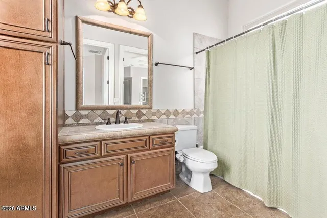 a bathroom with a granite countertop sink a toilet and a mirror