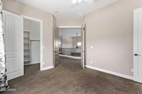 an empty room with windows and way to kitchen