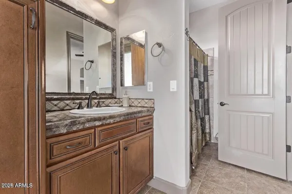 a bathroom with a granite countertop sink a mirror and a shower