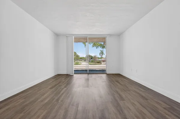 an empty room with wooden floor and window