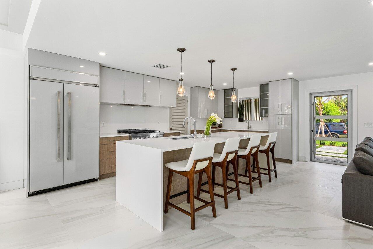902 Southwest 27th Place Boynton Beach, FL 33435 - Photo 5 of 52 a kitchen with stainless steel appliances kitchen island granite countertop a table chairs and a refrigerator