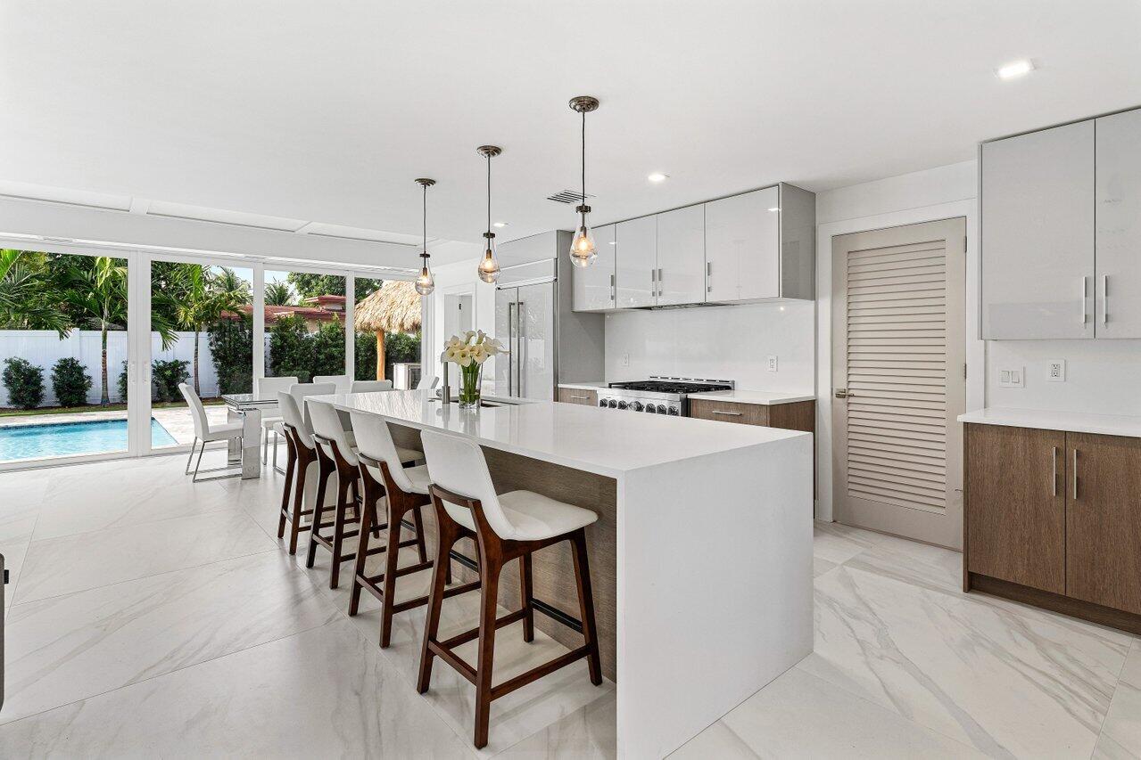 902 Southwest 27th Place Boynton Beach, FL 33435 - Photo 8 of 52 a kitchen with stainless steel appliances kitchen island granite countertop a table chairs and a refrigerator