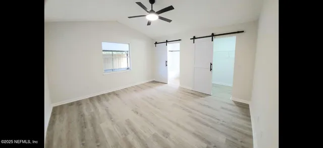 a view of empty room with wooden floor and fan