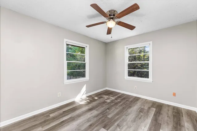 an empty room with a window and a ceiling fan