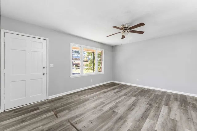 an empty room with windows and fan