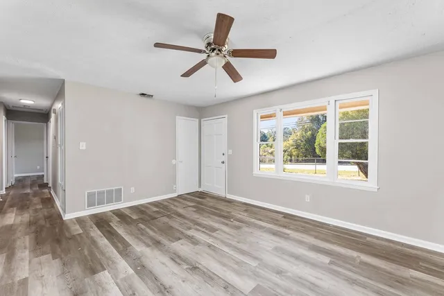 a view of empty room with wooden floor and fan