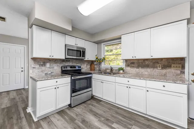 a kitchen with granite countertop white cabinets and white appliances