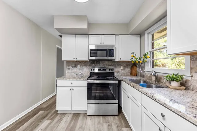 a kitchen with stainless steel appliances granite countertop a stove a sink and a microwave