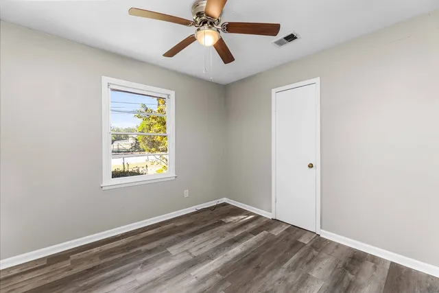 a view of empty room with window and ceiling fan