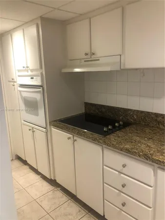 a kitchen with white cabinets and refrigerator