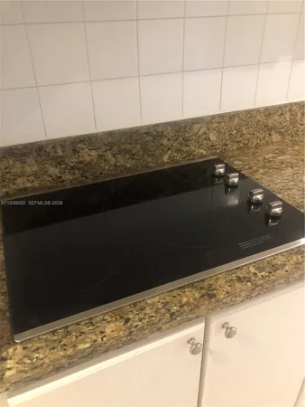 a view of kitchen island a sink wooden floor and a refrigerator