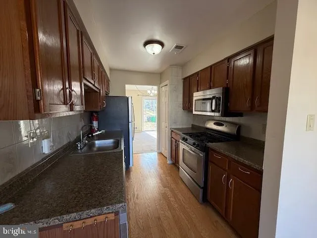 a kitchen with stainless steel appliances granite countertop a stove a sink and a refrigerator