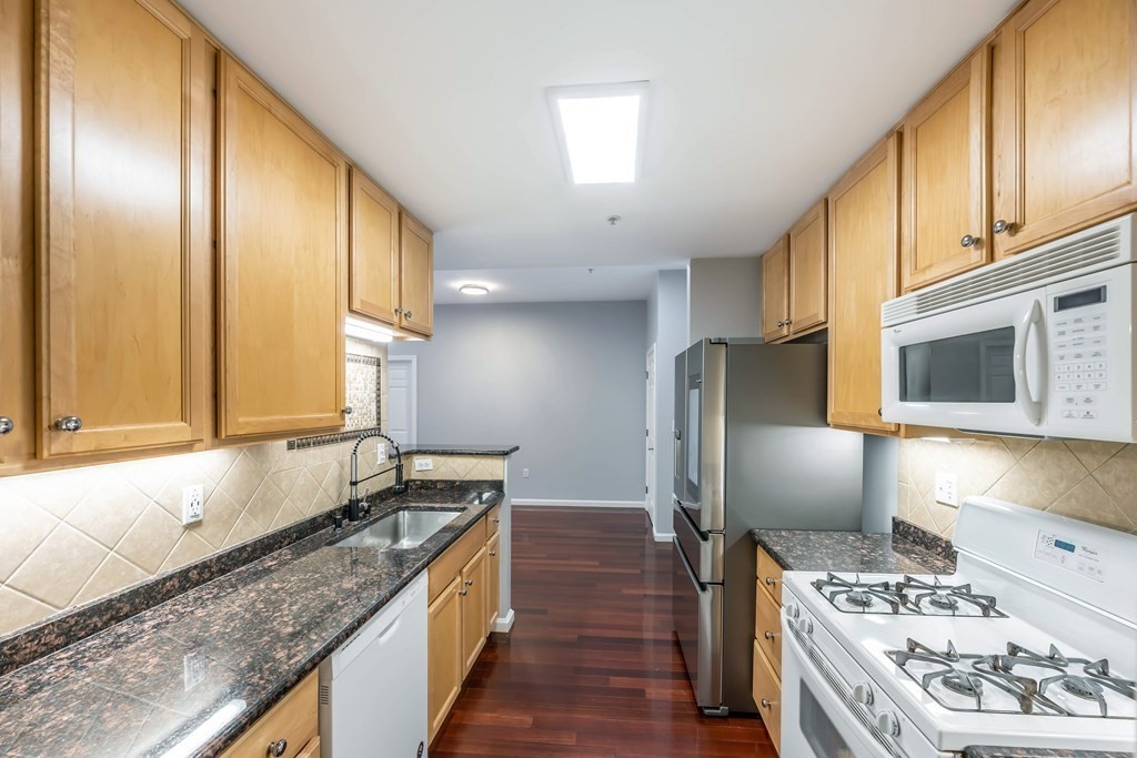 36 Village Road, Unit 112 Middleton, MA 01949 - Photo 8 of 27 a kitchen with stainless steel appliances granite countertop a sink stove and refrigerator