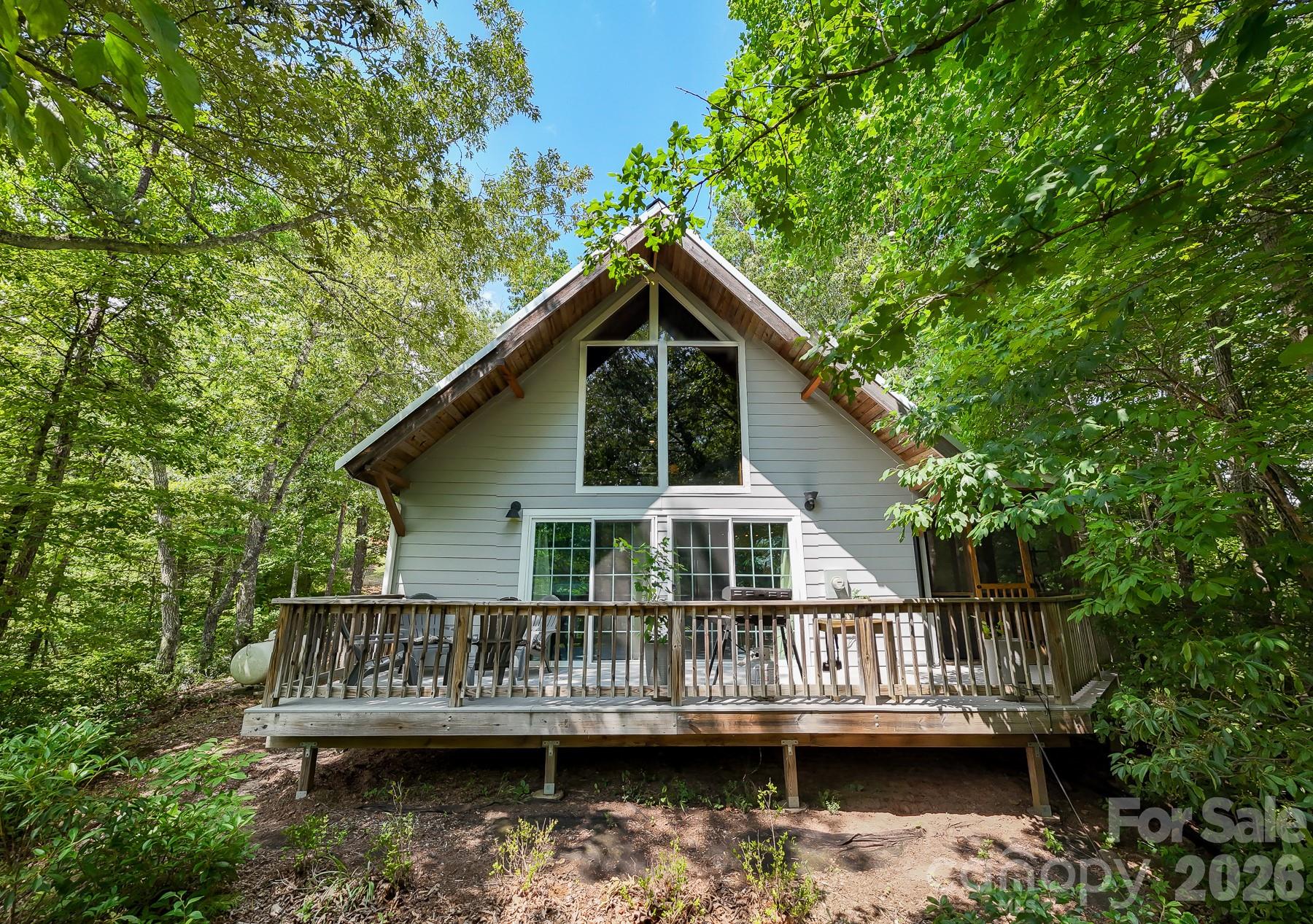 a view of house with a small yard and large trees