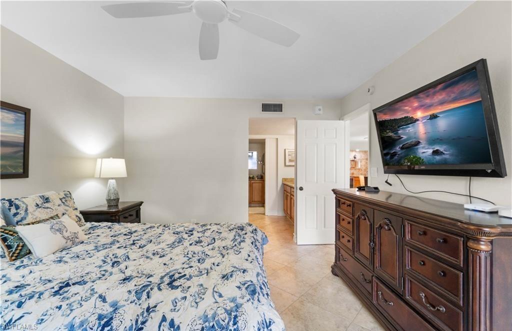 5890 Via Lugano, Unit 101 Naples, FL 34108 - Photo 13 of 22 a bedroom with a bed and a flat screen tv
