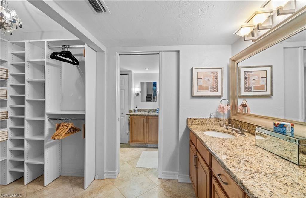 5890 Via Lugano, Unit 101 Naples, FL 34108 - Photo 14 of 22 a bathroom with a granite countertop sink a mirror and a bathtub