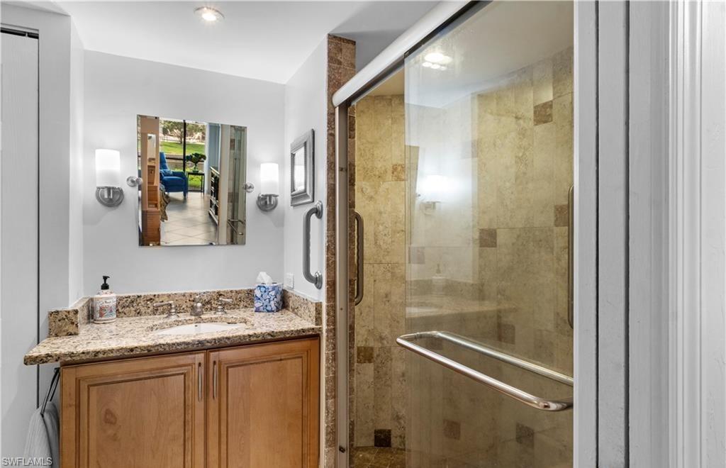 5890 Via Lugano, Unit 101 Naples, FL 34108 - Photo 15 of 22 a bathroom with a granite countertop sink a mirror and a shower