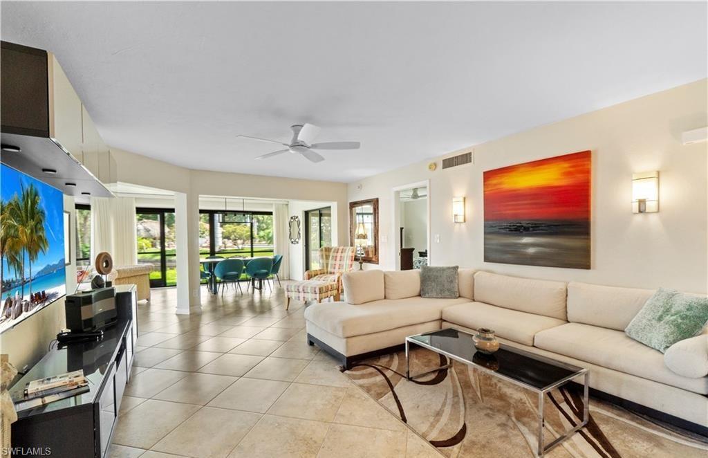 5890 Via Lugano, Unit 101 Naples, FL 34108 - Photo 3 of 22 a living room with furniture a flat screen tv and floor to ceiling window