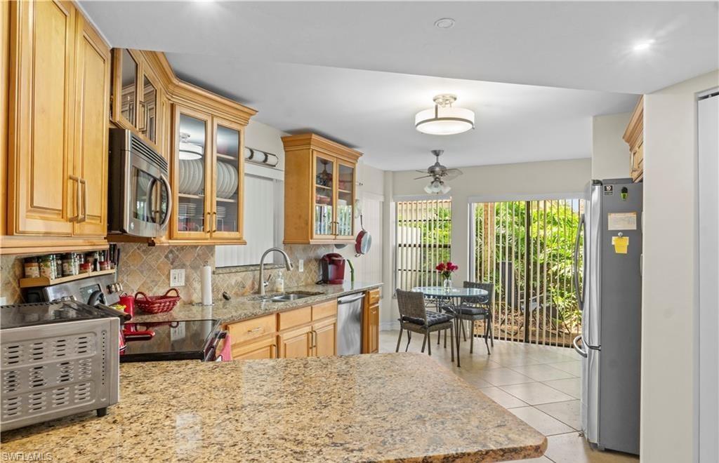 5890 Via Lugano, Unit 101 Naples, FL 34108 - Photo 4 of 22 a kitchen with stainless steel appliances granite countertop sink stove and white cabinets