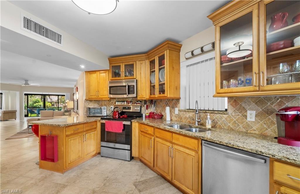 5890 Via Lugano, Unit 101 Naples, FL 34108 - Photo 5 of 22 a kitchen with kitchen island granite countertop a sink stove and cabinets