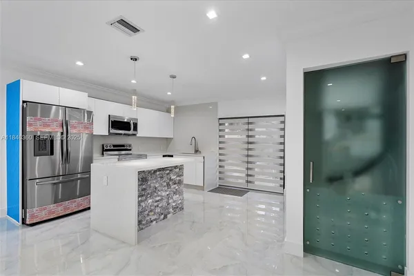 a large kitchen with stainless steel appliances granite countertop a stove top oven a sink dishwasher and a refrigerator with wooden floor