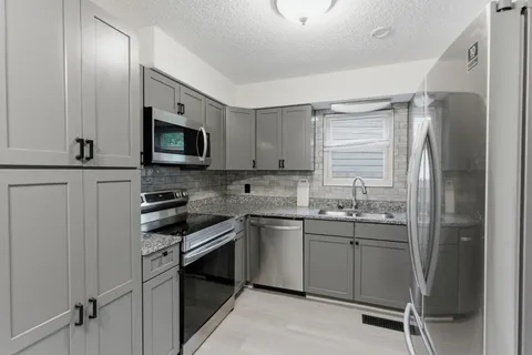 a kitchen with stainless steel appliances a sink cabinets and a window