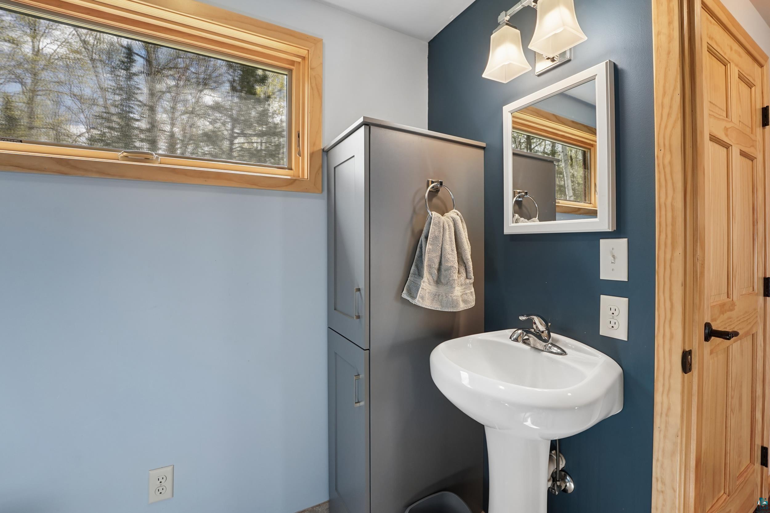 89095 West Romans Point Road Herbster, WI 54844 - Photo 21 of 30 Pedestal sink with chrome faucet, complemented by a tall, built-in storage cabinet with satin nickel hardware