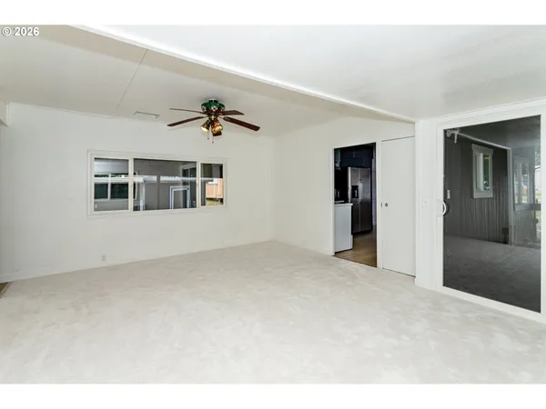 a view of a big room with windows and chandelier fan