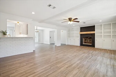 an empty room with windows fireplace and a chandelier fan