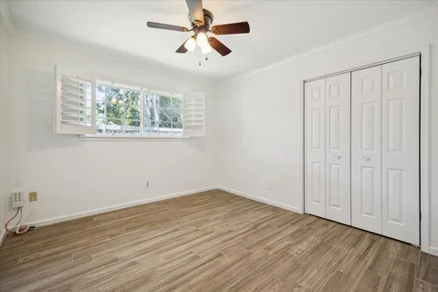 an empty room with wooden floor chandelier fan and windows