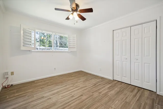 an empty room with wooden floor chandelier fan and windows