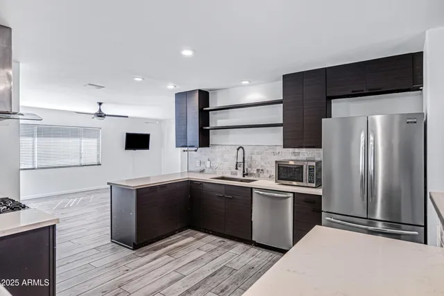 a kitchen with stainless steel appliances a sink a stove a refrigerator and cabinets