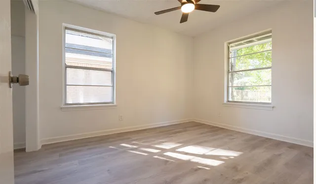 en empty room with windows and chandelier fan