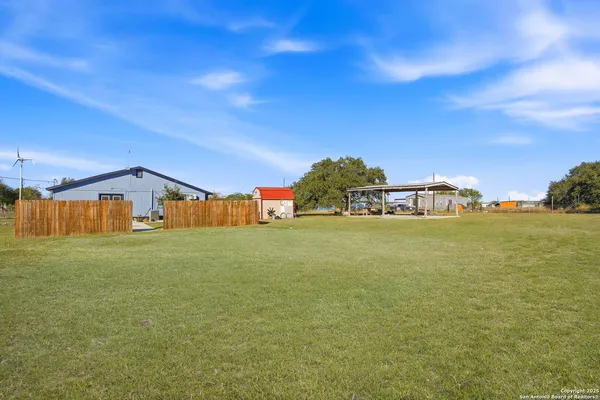 a view of a patio with a table and chairs under an umbrella with a small yard