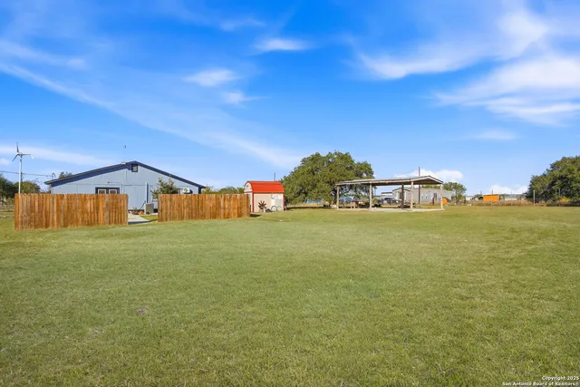 a view of a patio with a table and chairs under an umbrella with a small yard
