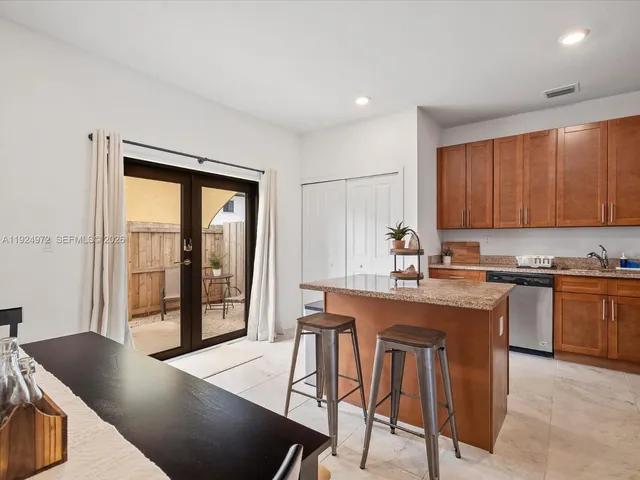 a kitchen with stainless steel appliances granite countertop a stove a refrigerator a sink a dining table and chairs with wooden floor